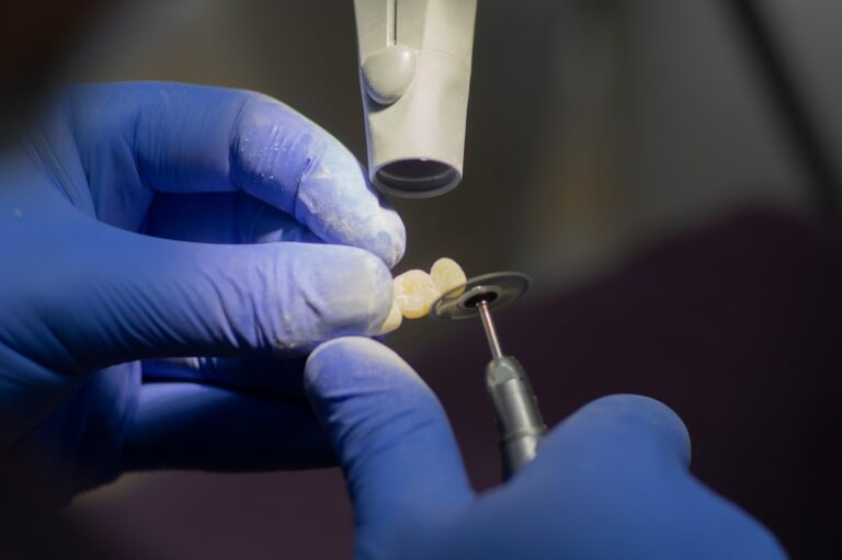 A dentist fits a dental bridge model on a patient’s prepared teeth in a dental treatment room.